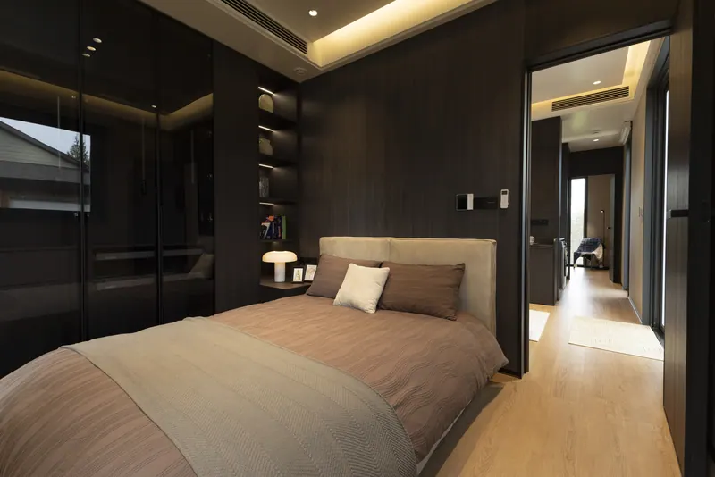 Ember bedroom with lit shelving and a view down the hall