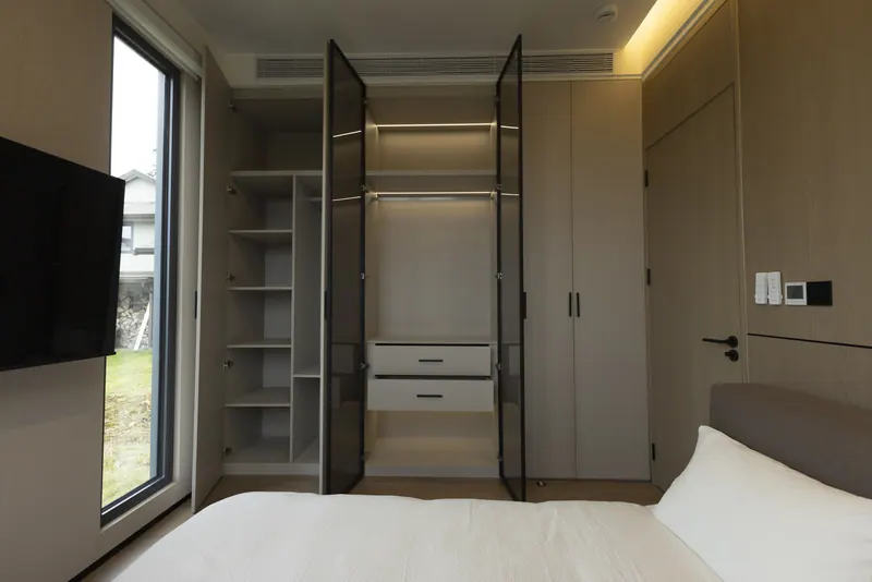 Floor-to-ceiling glass-door closet with lit shelves