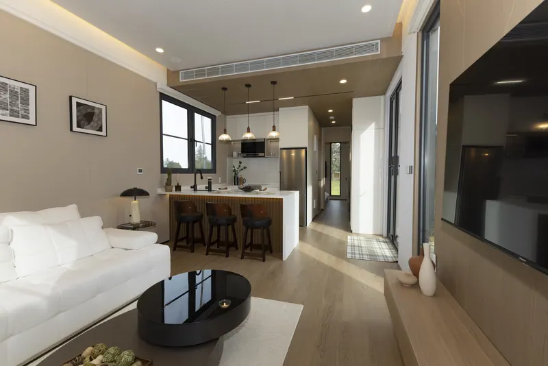 Solace living area with a white sofa, and the kitchen and bar stools beyond