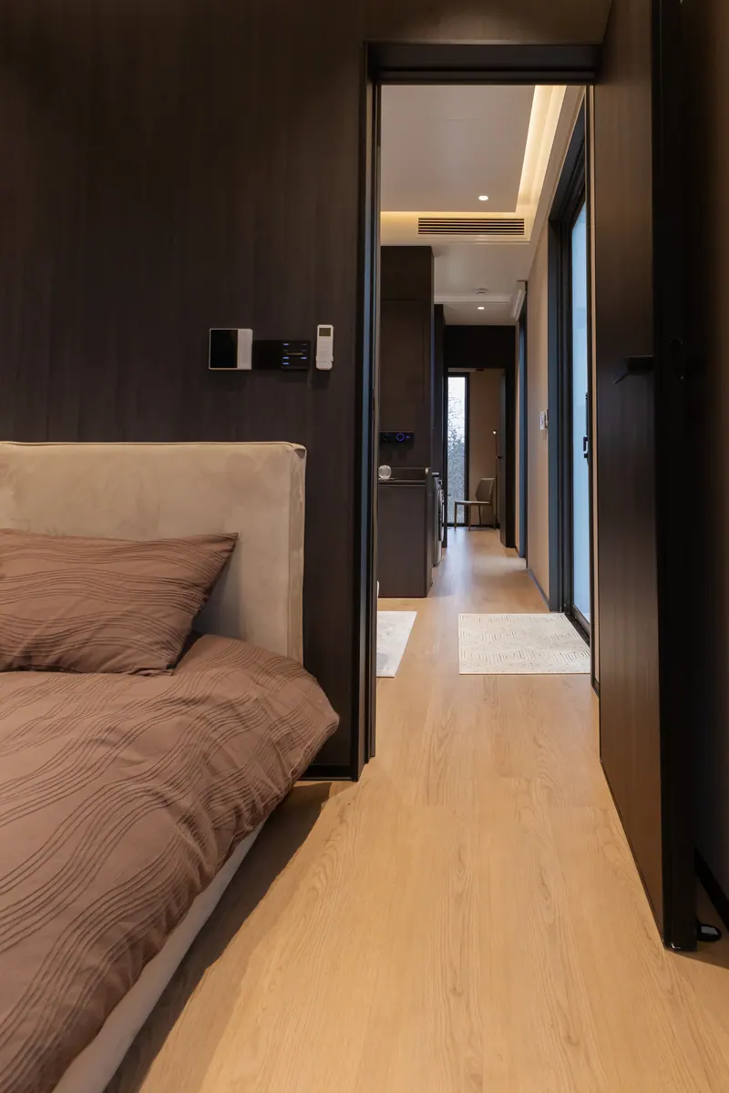 View from the bed down the hallway to the end window, dark finish