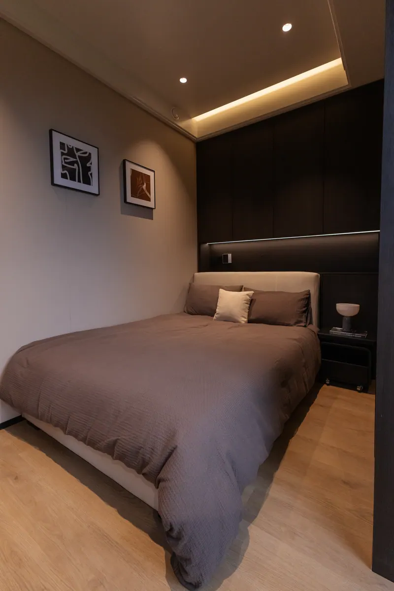 Dark-finish bedroom with framed art and cove lighting