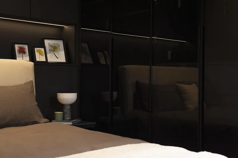 Bedside with a lit shelf and a glossy wardrobe, dark finish