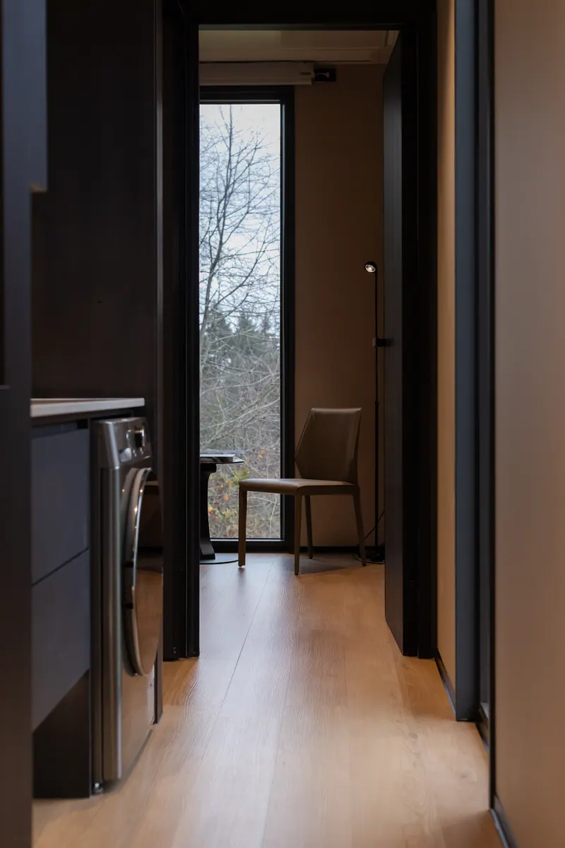 Hallway from the laundry to the end window and a reading chair, dark finish