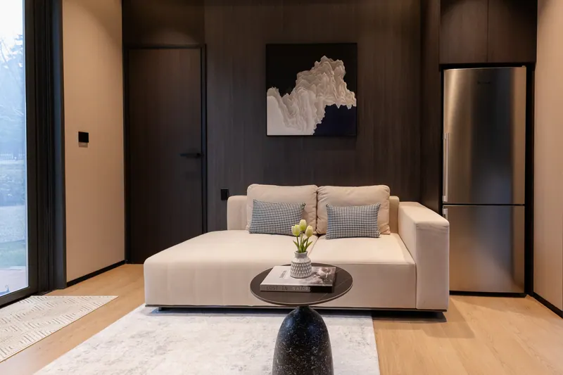 Dark-finish living area with a cream daybed sofa and art