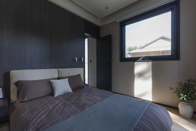Dark-finish second bedroom with a square window