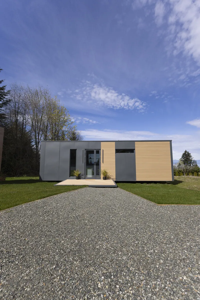 A show home under a big sky, with the gravel drive leading to the deck