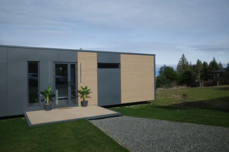 Front of a show home with planters and the ocean on the horizon