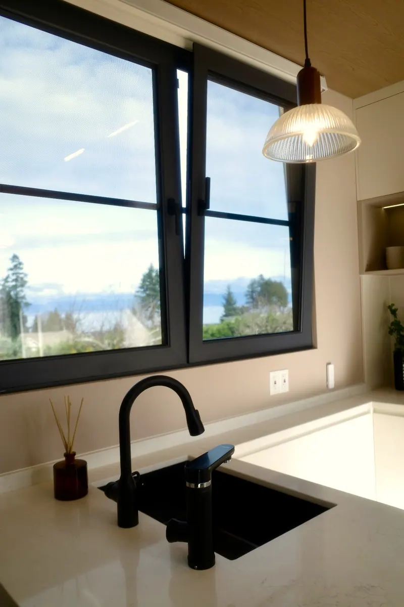 Kitchen window over the sink with a view of the ocean and mountains