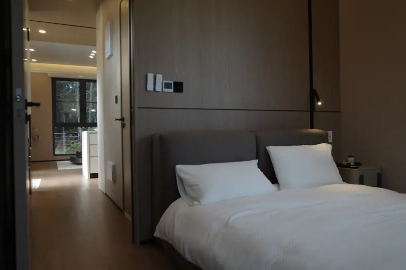 Light-finish bedroom with the door open to the hall and living room