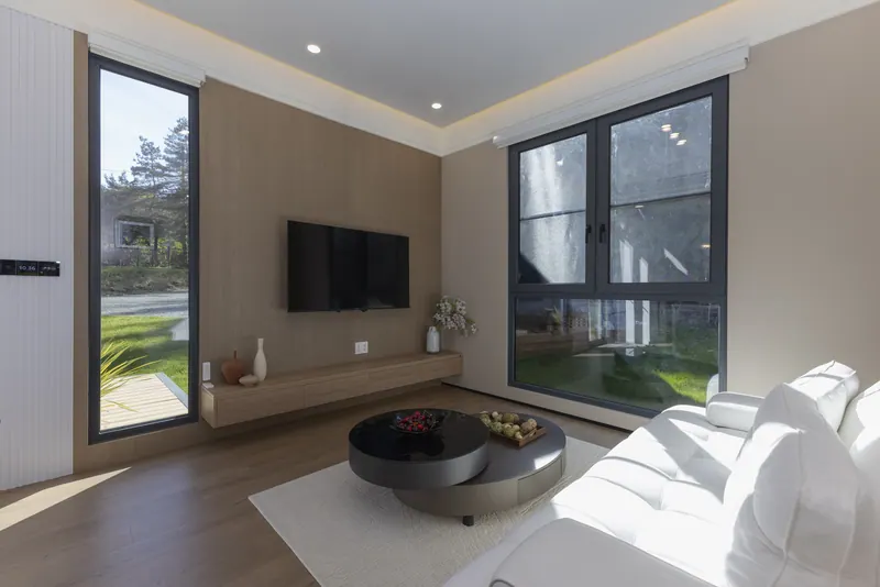 Light-finish living room with the TV wall between a tall slot window and a large window