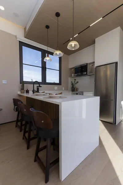 Quartz waterfall kitchen island with stools and pendant lights
