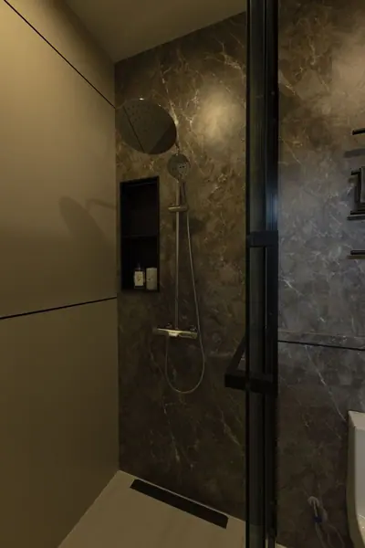 Glass shower with a rain head and a lit niche