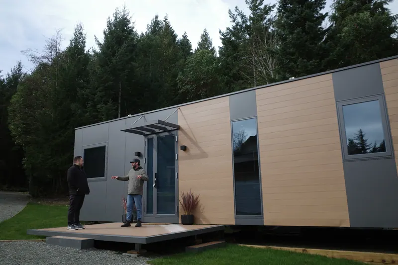 A host talking with a visitor on the deck of a show home