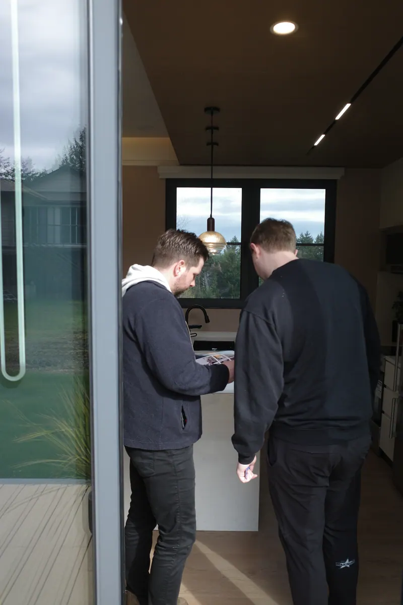 Two visitors looking at a phone together just inside the door of a show home