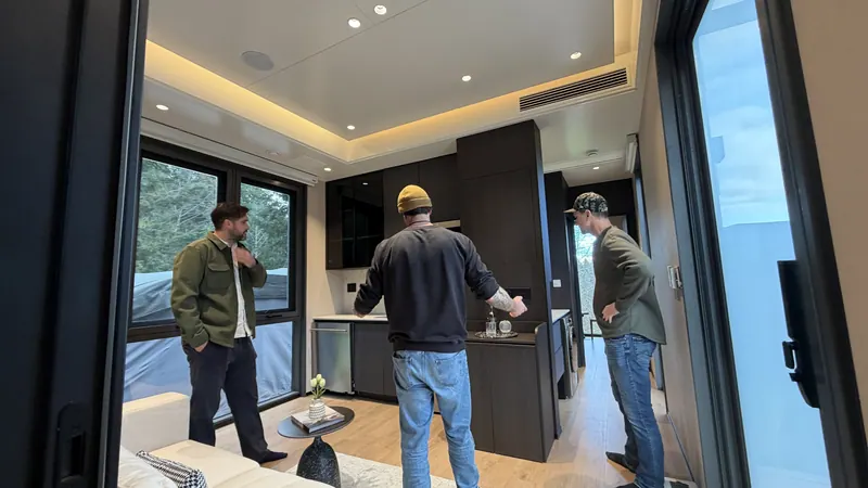 Three visitors talking in the dark-finish kitchen