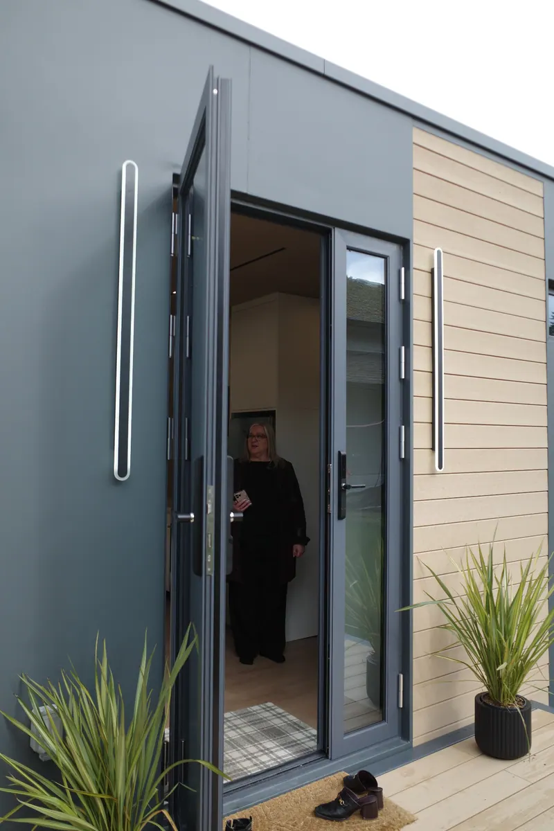 A visitor standing just inside the open door of a show home