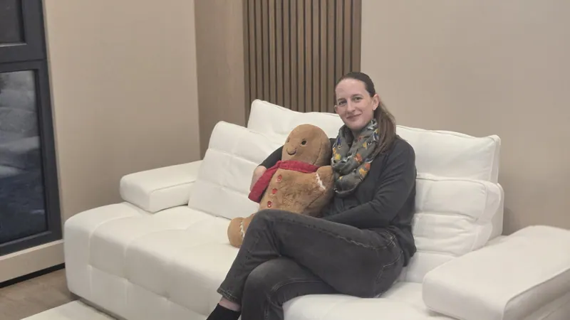 A visitor relaxing on the white sofa with a large teddy bear