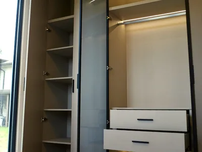 Open floor-to-ceiling closet with lit shelves, a lit hanging rail and two drawers