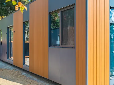 Close-up of a new Cueva home's aluminum wall panels, wood-look accent cladding and a large window