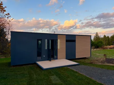 A finished Cueva home at sunset with its deck, lit entry and wood-look accent panels
